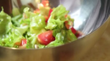 Bir kadının taze salatasını metalik servis kasesine aktardığı videoyu kapat.