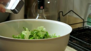 Taze bir salatanın üzerine tuz serpildiğini gösteren yavaş çekim videosu.