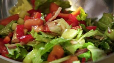 Yavaş çekimde taze salatanın parlak metalik servis kâsesine aktarıldığı videoyu kapat.