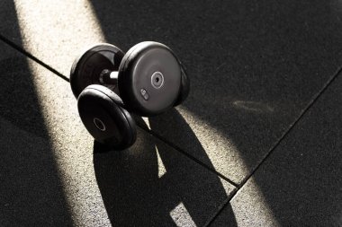 Üstüste istiflenmiş 5 kiloluk iki dambılın, benekli güneş ışığıyla aydınlatılmış fotoğrafını kapat.