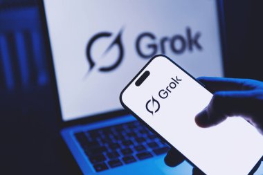 İzmir, Türkiye - 21 Ocak 2026: Grok AI uygulamasının açık olduğu modern bir akıllı telefonu tutmak, arka planda Grok arayüzünü gösteren modern bir dizüstü bilgisayar