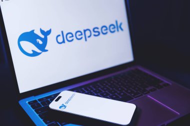 İzmir, Türkiye - 21 Ocak 2026: Beyaz arka planda DeepSeek AI logosu olan bir dizüstü bilgisayarın fotoğrafı, klavyesinde dinlenen modern akıllı telefon da beyaz arkaplanda DeepSeek logosu gösteriyor.