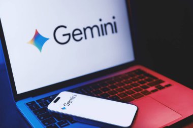 Izmir, Turkey - Jan 21 2026: Photo of a laptop with Gemini AI logo on white background screen, modern smartphone placed on its keyboard also showing Gemini logo on white background.