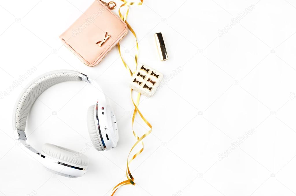 Music headphones, gold ribbon and blush handbag on white background top