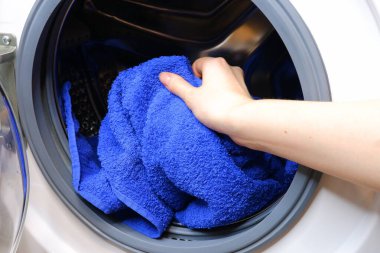 İnsan çamaşır makinesine bir şeyler koyar. Teçhizatlar. Temizlik. Yıka. 