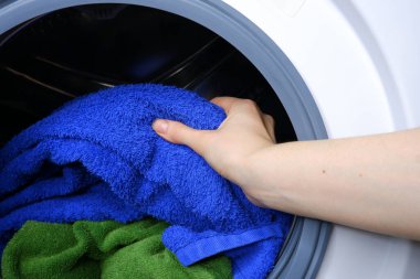 Kız çamaşır makinesinden çamaşırları çıkarıyor.