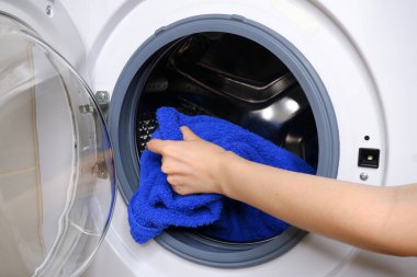 Kız çamaşır makinesinden çamaşırları çıkarıyor.