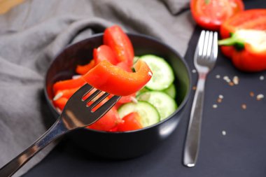 Bulanık arka planda bir çatalda kırmızı biber dilimi. Sebze salatası.