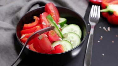 Bir parça taze salatalık bir çatalın üzerinde dönüyor. Arka plan bulanık. Salata..