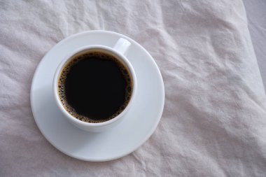 Beyaz yatakta bir fincan siyah kahve..