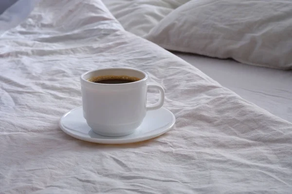 Λευκό Φλιτζάνι Μαύρο Καφέ Ένα Λευκό Κρεβάτι — Φωτογραφία Αρχείου