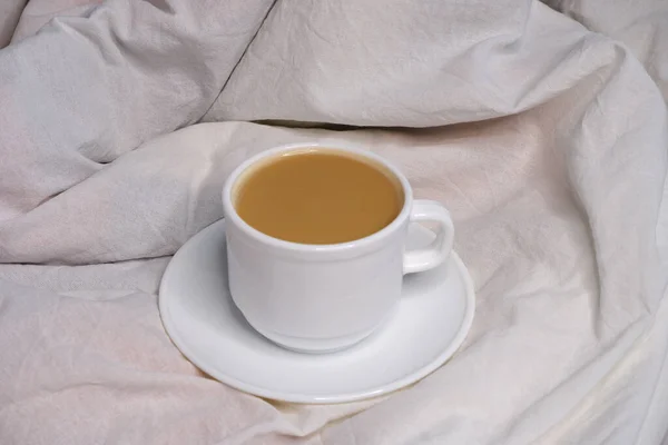 Coffee with milk on white bed linen.