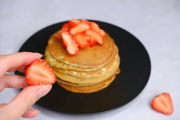 Gadis Memegang Stroberi Tangannya Dengan Latar Belakang Kabur Pancake Dengan — Stok Foto