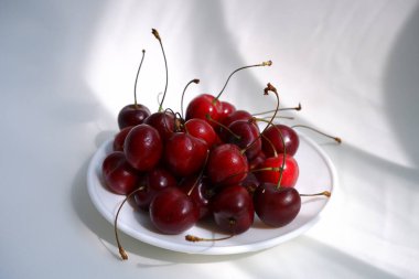 Hafif arka planda güzel bir vişne. Güneşin ışınları böğürtlenlerin üzerine düşer.