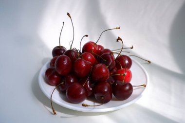 Hafif arka planda güzel bir vişne. Güneşin ışınları böğürtlenlerin üzerine düşer.