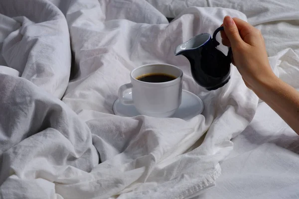 女孩把牛奶倒入一杯咖啡中 早餐在床上 — 图库照片