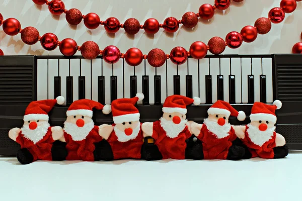 Piyano ve Noel süslerinin bulanık arka planında komik Noel Baba oyuncakları