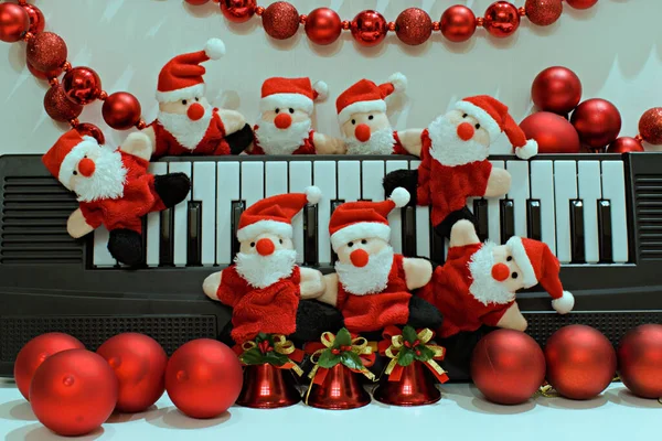 Piyano ve Noel süslerinin bulanık arka planında komik Noel Baba oyuncakları