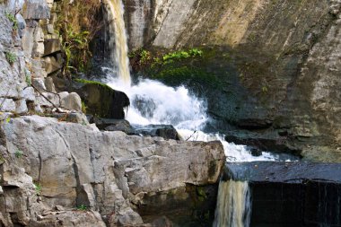 Granit taşların üzerine şelale ve bulanık bir su akıntısı.