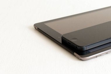 Elektronik aletler, akıllı telefon ve tablet, bulanık beyaz arkaplan üzerine siyah.