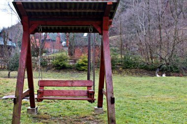 Modern kırsal sonbahar manzarasında yeşil çayır üzerinde ahşap salıncak