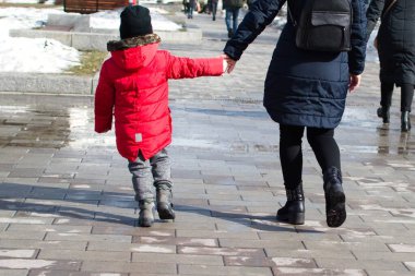 Küçük çocuk annesiyle birlikte Spring City caddesinde yürüyor.