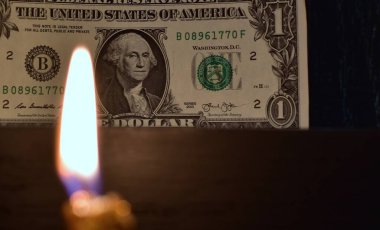Bir dolarlık banknot ön planda bulanık mum alevi ile yakın çekim