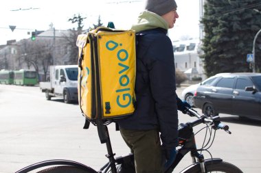 Ukraine Zhytomyr March 26, 2021. Guy with yellow backpack of delivery service on bike on blurred background of city traffic