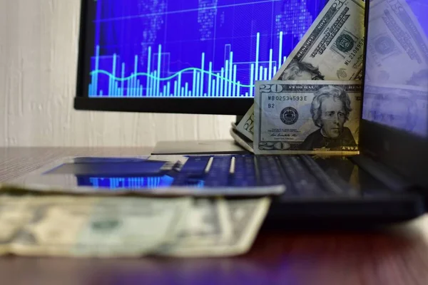 Bilgisayar ekranının bulanık arka planında 20 dolarlık banknotlar ve hisse senedi grafiği. Bulanık arkaplan