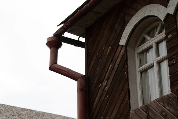 旧废弃房屋屋顶下的排水管和窗户 — 图库照片