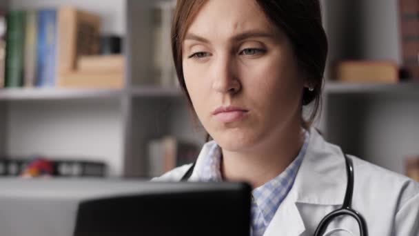 Close-up de médico cansado no computador experimenta dor e desconforto no pescoço. Médica concentrada no escritório trabalhando no laptop digitando no teclado faz uma pausa e toca seu pescoço — Vídeo de Stock