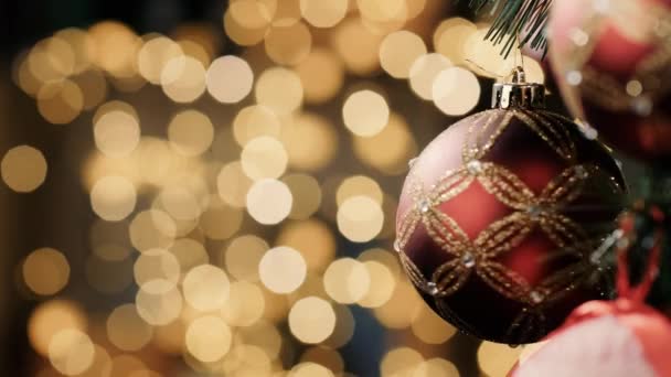 Mainan Natal bola berputar di pohon Natal, di latar belakang ada banyak lampu buram beberapa di antaranya berkedip. Close-up — Stok Video