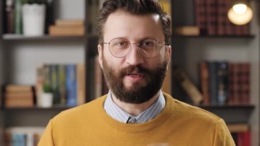 Online consultation and remote presentation concept. Portrait of positive man with glasses looking at camera and explains something, while actively gesturing with his hands. Front view and close-up