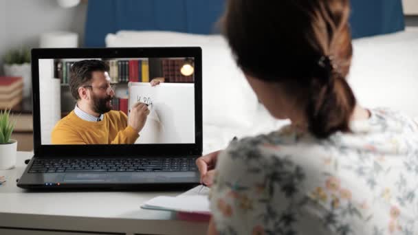 Afstandsonderwijs, online les, training video, online onderwijs concept. Vrouw zit aan het bureau en maakt notities, op laptop scherm leraar spreekt en schrijft formule van orthofosforzuur op whiteboard — Stockvideo