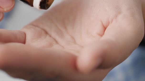 Dos grandes píldoras cuadradas blancas caen en la palma de la mano del frasco de pastillas. Primer plano, vista frontal, composición central — Vídeo de stock