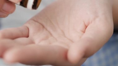 İki büyük açık kahverengi yuvarlak hap hap şişesinden avuç içine düşer. Yakın çekim, ön görüntü, merkez kompozisyon