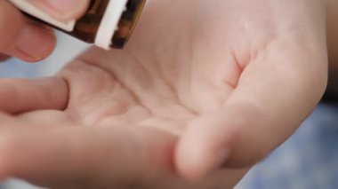 İki büyük beyaz hap oval uzamış şekiller hap şişesinden avuç içine düşer. Yakın çekim, ön görüntü, merkez kompozisyon