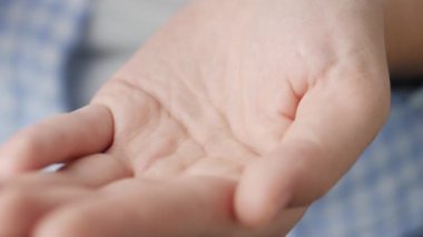 İki küçük turuncu yuvarlak hap ilaç şişesinden avuç içine düşer. Yakın çekim, ön görüntü, merkez kompozisyon