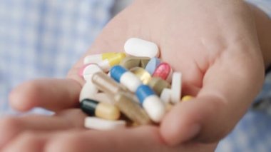 Avucunun içinde çeşitli şekil ve renklerden oluşan tablet ve kapsüller var. Yakın çekim, ön görüntü, merkez kompozisyon