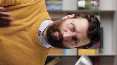 Man show STOP, NO. Vertical video of serious displeased bearded man in glasses in office or apartment looking at camera and shows his palm STOP. Close-up and slow motion