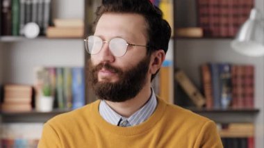 Man thinking, brainstorm, good idea concept. Concentrated bearded man in glasses in office or room in apartment with pensive face looking around thinks and brainstorm. Close-up and slow motion