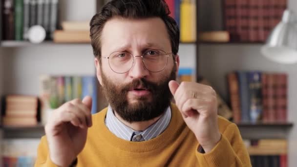 Man is dancing. Positive bearded man office worker in glasses in office or apartment room looking at camera and dances and sings along. Close-up and slow motion — ストック動画