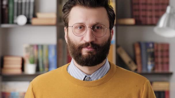 Man nods in agreement. Positive bearded man in glasses in office or apartment romm looking at camera and nods his head positively, signaling YES or HELLO. Close-up and slow motion — Vídeo de stock
