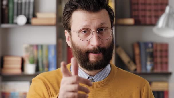 Man threatens with his finger. Serious frowning bearded man in glasses in office or apartment room looking at camera and points menacingly with his index finger. Close up and slow motion — Stock Video