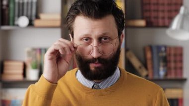 Skepticism, sarcasm emotion. Bearded man in glasses in office or apartment room looking at camera and expressing his skeptical attitude and discontent with his look. Close up and slow motion