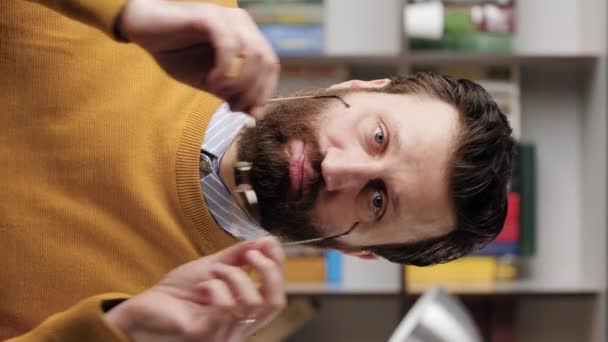 FACEPALM in Verbindung setzen. Das vertikale Video zeigt einen erstaunten bärtigen Mann mit Brille im Büro oder in der Wohnung, der in die Kamera blickt und sein Gesicht mit den Händen bedeckt, die seine Fassungslosigkeit ausdrücken. Nahaufnahme und Zeitlupe — Stockvideo