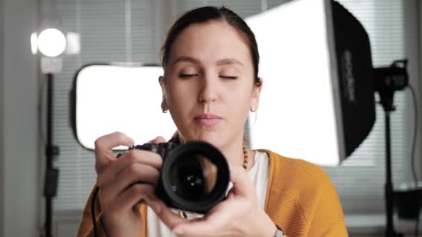 Online lesson, online learning, video call, internet education concept. Woman photographer or videographer is in photo studio, holds camera in her hands and looking into webcam and talking — Stock Video