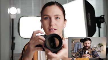 Online ders, video görüşmesi, internet eğitimi konsepti. Kadın fotoğrafçı ya da kameraman fotoğraf stüdyosunda elinde kamerayla web kamerasına bakıyor ve orta yaşlı bir öğrenciyle konuşuyor.