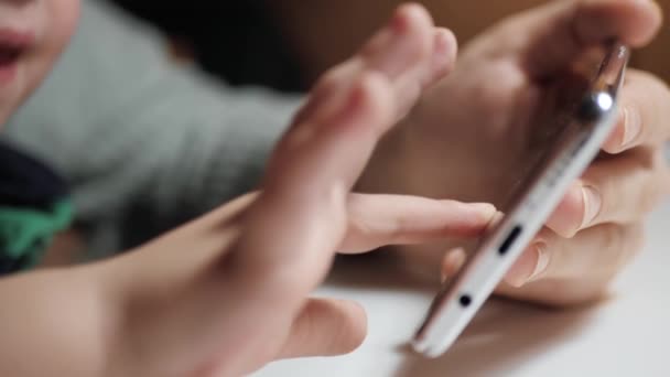 Toques de mão de bebê na tela do telefone. Close-up da mão da criança e mão da mulher adulta está segurando smartphone, pequenos dedos da criança se movem na tela. Movimento lento — Vídeo de Stock