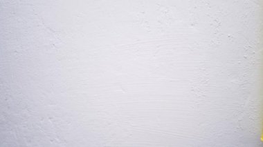 Boya duvarı. Sarı renkli paten, beyaz duvarı boyamak için yavaşça yatay hareket ediyor. Yakın çekim ve yavaş çekim